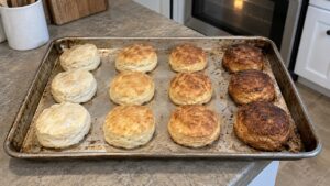 A sheet of baked biscuits showing uneven browning from one side of the tray to the other
