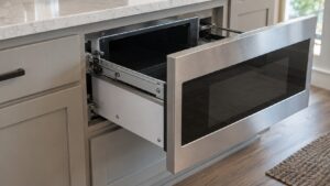 A built-in drawer-style microwave partially pulled open, showing the side rails along the cabinet opening
